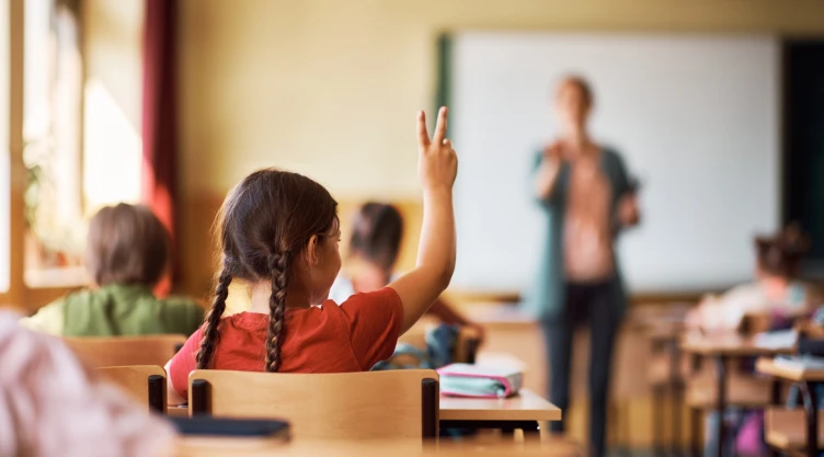 Alumnos en un aula con una maestra.