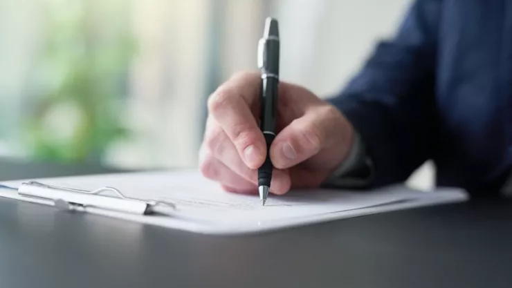 Una persona firma unos papeles.