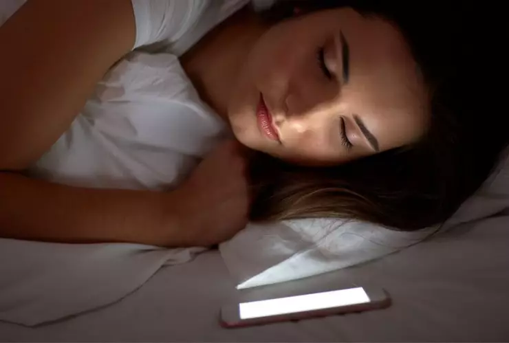 Mujer que duerme con celular en la almohada